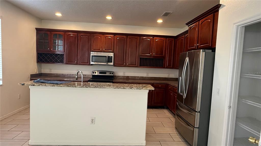 4484 Philadelphia Circle Kissimmee, FL 34746 - Photo 5 of 56 a kitchen with stainless steel appliances granite countertop a refrigerator and a stove top oven
