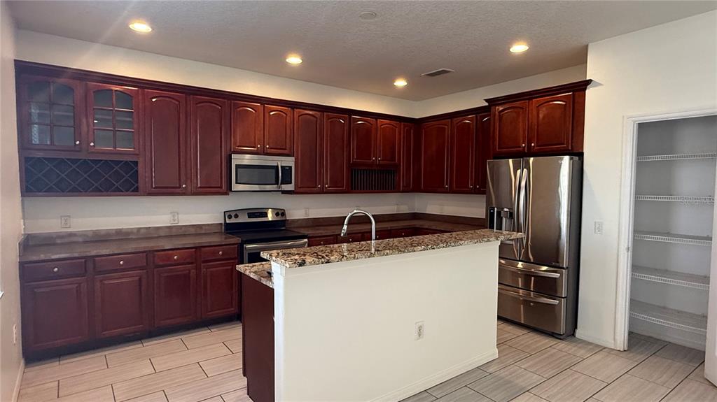 4484 Philadelphia Circle Kissimmee, FL 34746 - Photo 6 of 56 a kitchen with stainless steel appliances granite countertop a refrigerator stove a sink and dishwasher