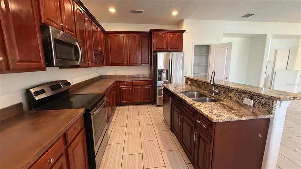 4484 Philadelphia Circle Kissimmee, FL 34746 - Photo 7 of 56 a kitchen with kitchen island granite countertop a sink stove and refrigerator