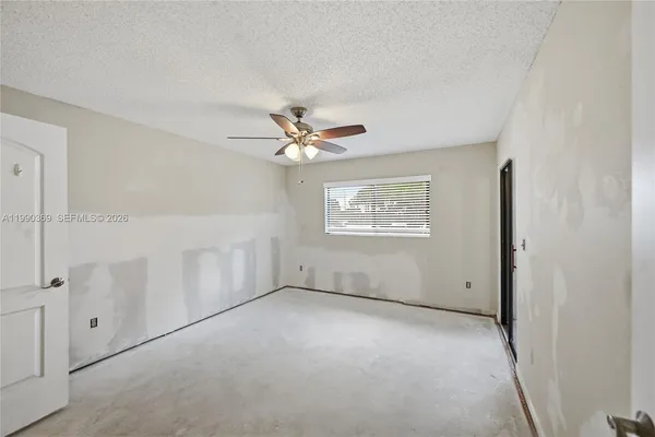 an empty room with windows and fan