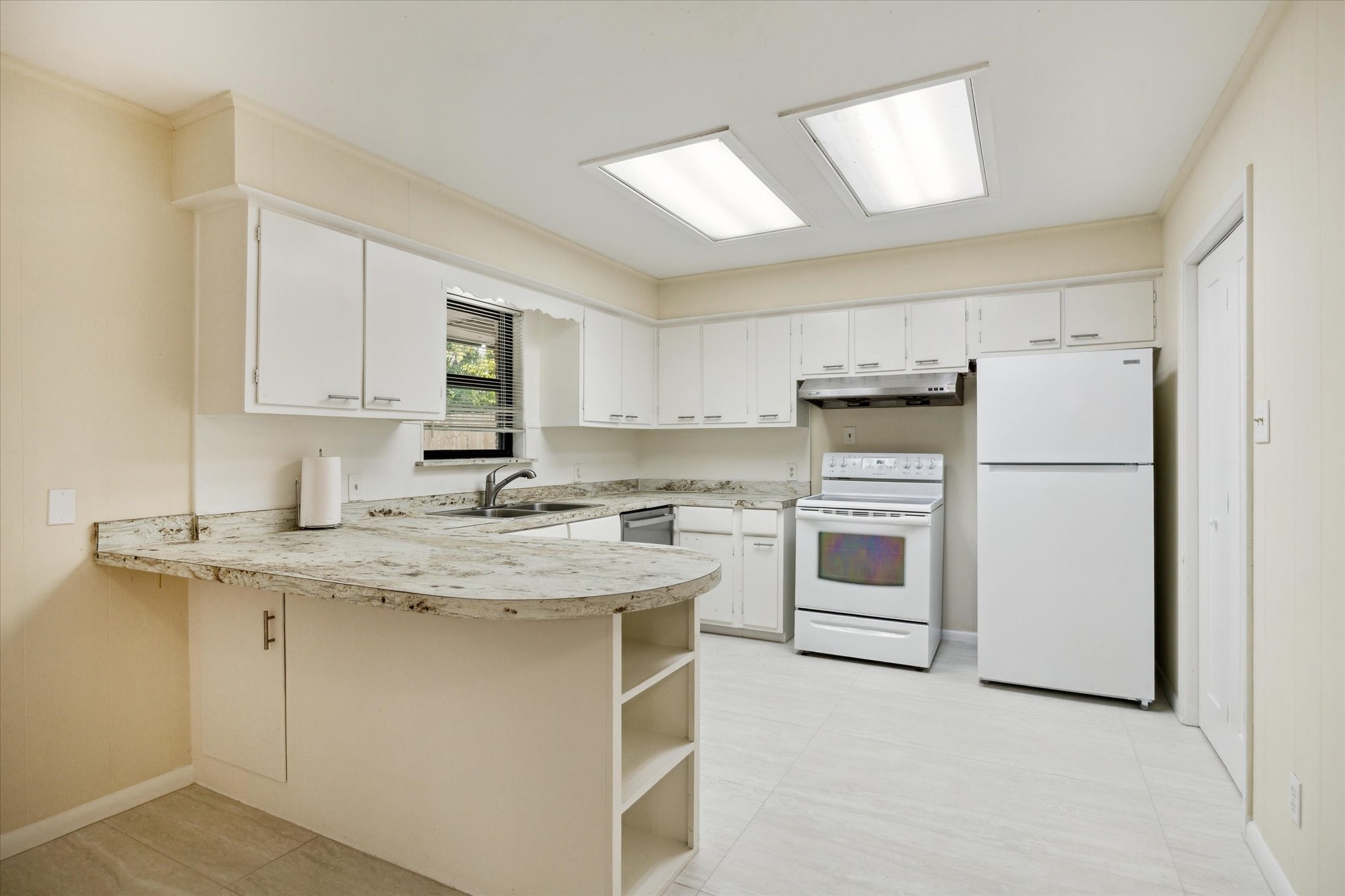8907 Autauga Street Houston, TX 77080 - Photo 8 of 20 Bright, spacious kitchen with white cabinetry, and a breakfast bar. Equipped with a white stove and refrigerator, it features ample storage and a convenient layout.