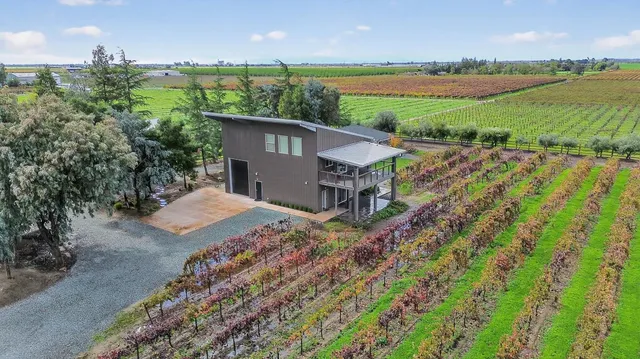 a view of a house with a yard and lawn chairs under an umbrella
