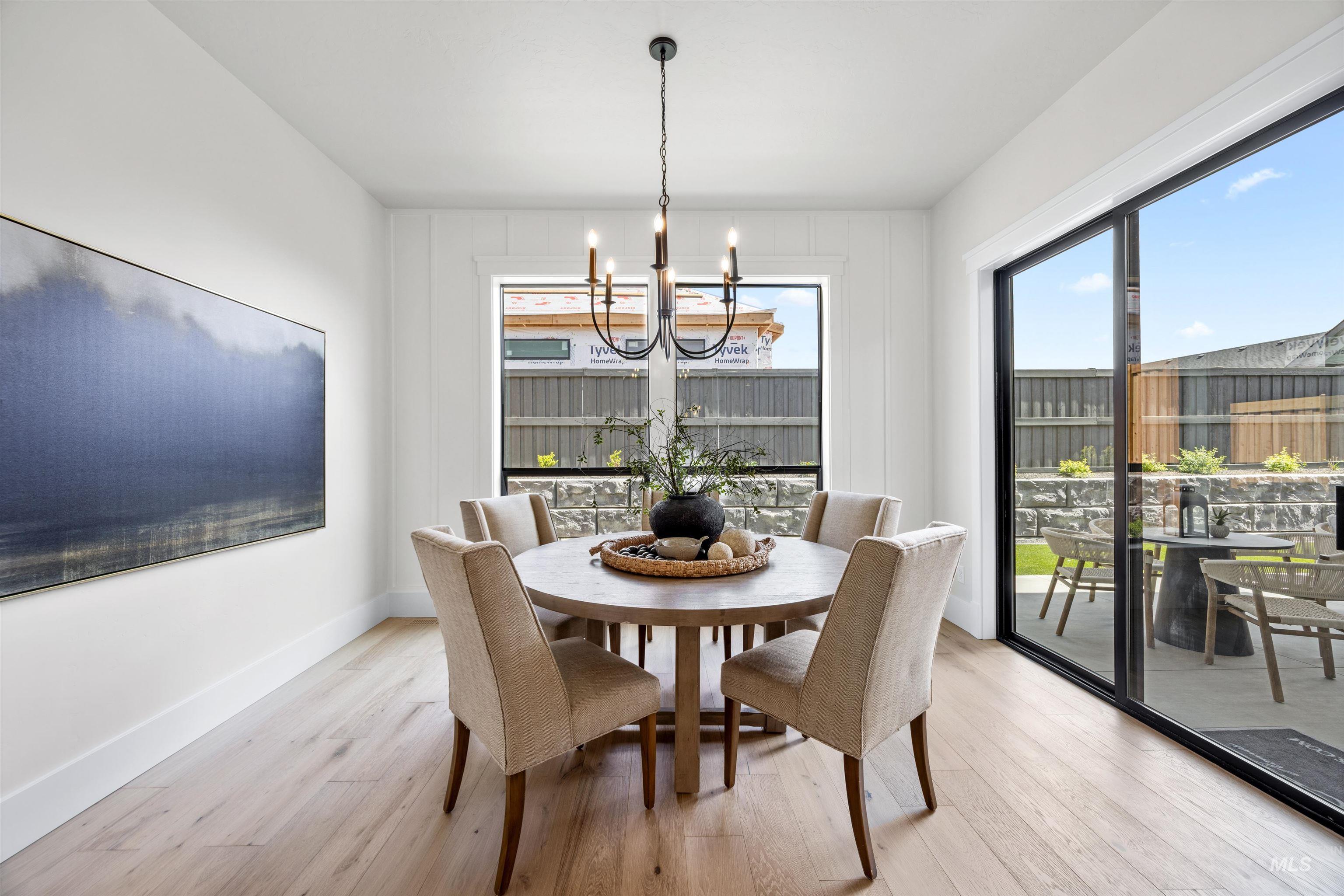 5940 South Pinpoint Way Meridian, ID 83642 - Photo 17 of 40 Wood-finish flooring, white wall paneling, a multi-pane window, and a glass slider to the exterior patio