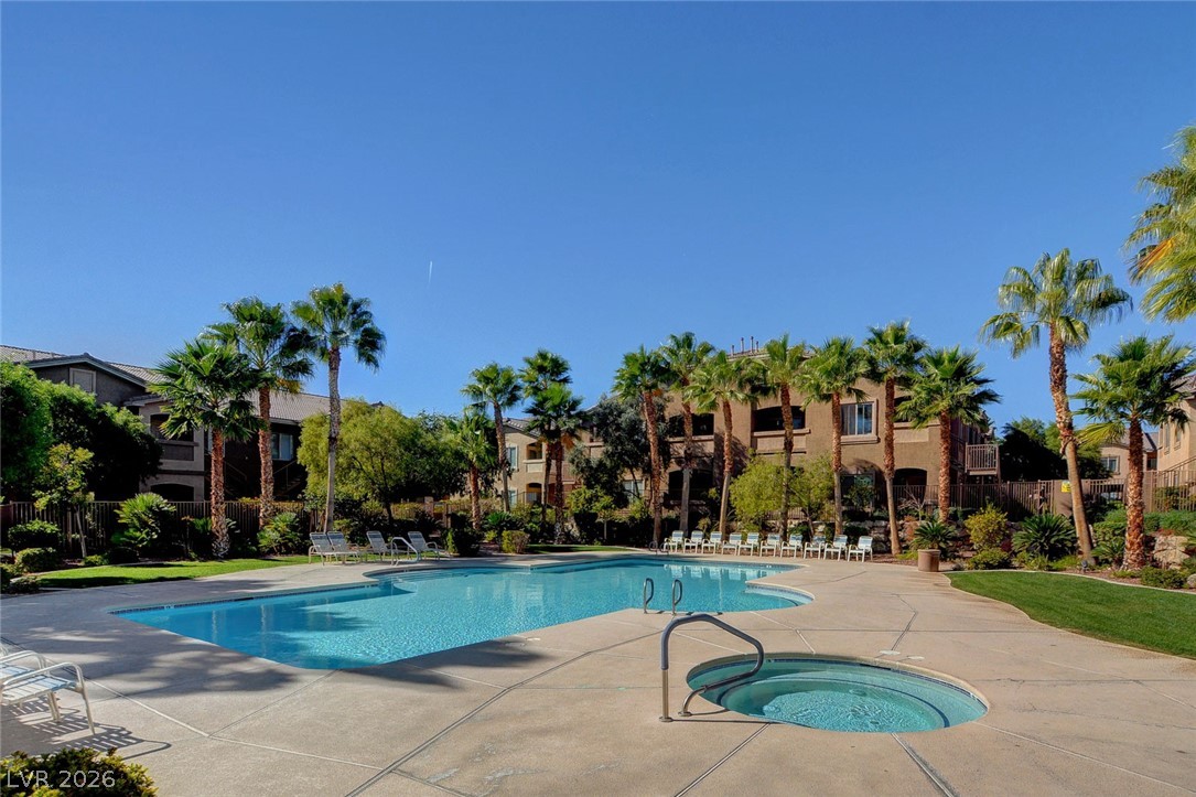 8985 South Durango Drive, Unit 2187 Las Vegas, NV 89113 - Photo 70 of 73 A tranquil community pool with a relaxing spa, embraced by lush landscaping and towering palm trees.