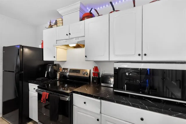 a kitchen with stainless steel appliances a stove refrigerator sink and wooden floor