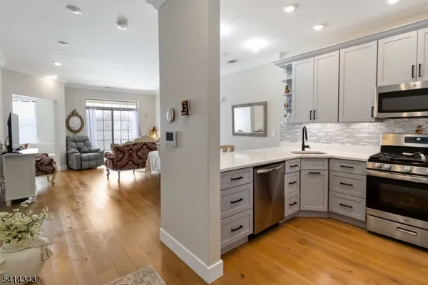 a kitchen with stainless steel appliances granite countertop a stove top oven a sink dishwasher and a refrigerator with wooden floor