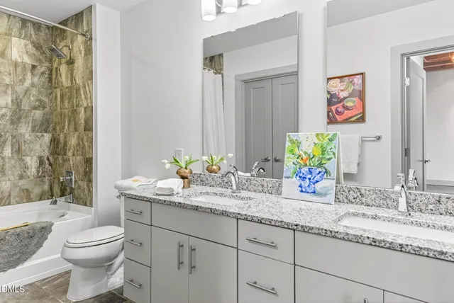 a bathroom with a granite countertop sink a toilet a mirror and shower