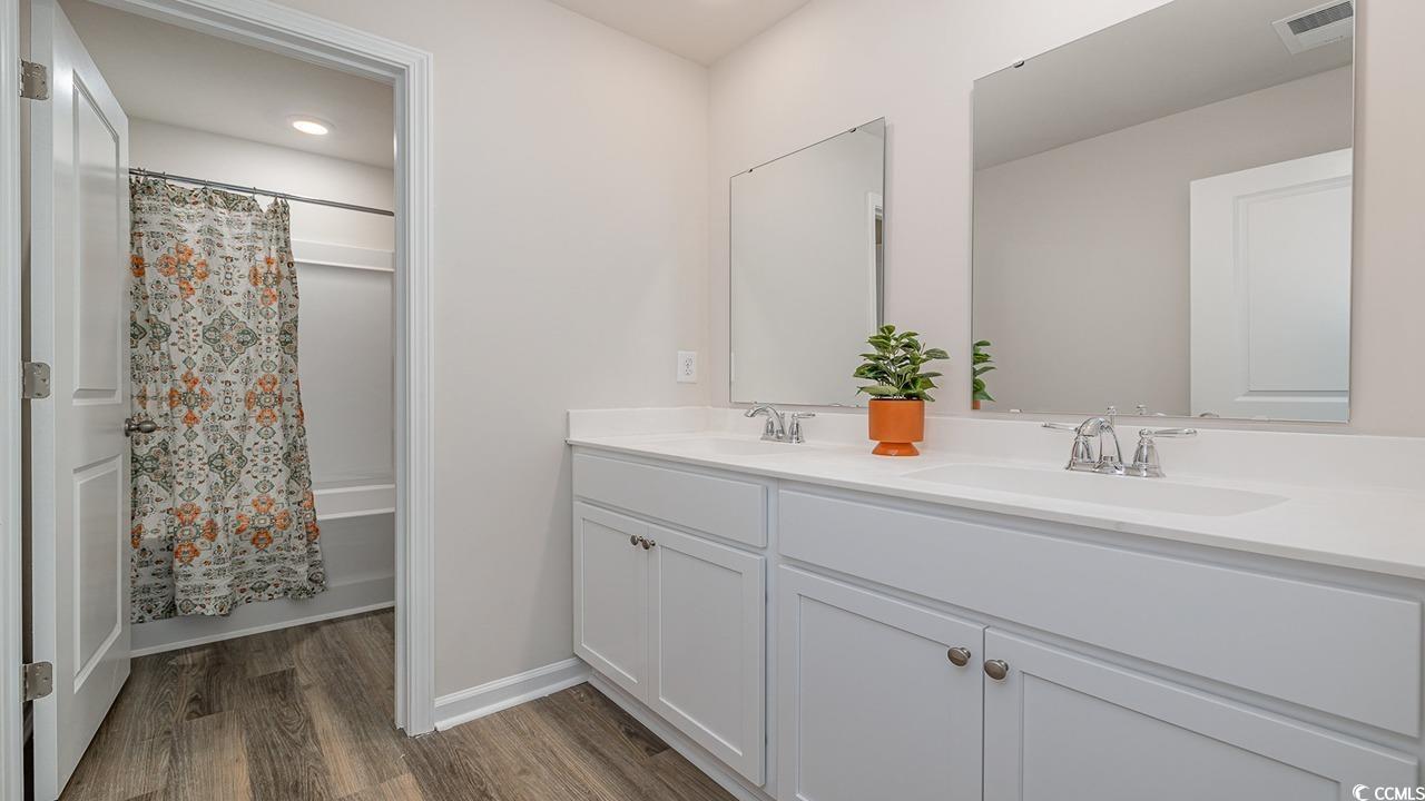 303 Ridley Street Longs, SC 29568 - Photo 30 of 31 Full bath featuring double vanity, shower / bathtub combination with curtain, and dark wood-type flooring