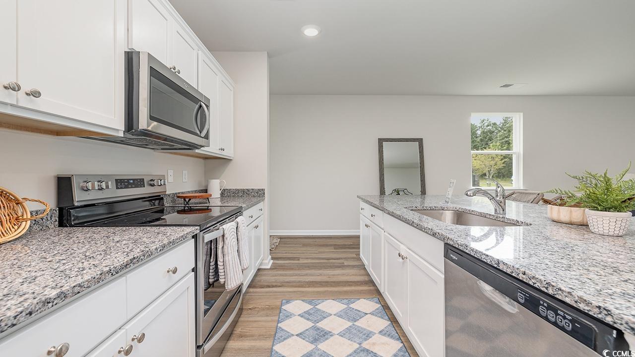 303 Ridley Street Longs, SC 29568 - Photo 6 of 31 Kitchen with appliances with stainless steel finishes, white cabinets, light stone counters, light wood-style floors, and recessed lighting
