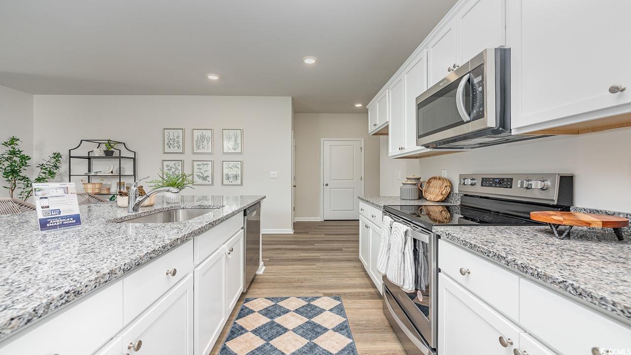 303 Ridley Street Longs, SC 29568 - Photo 7 of 31 Kitchen with appliances with stainless steel finishes, white cabinets, light stone counters, recessed lighting, and light wood finished floors
