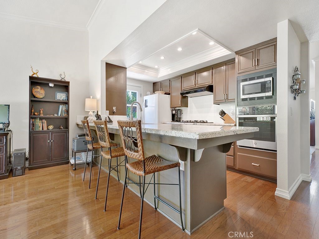 a open kitchen with stainless steel appliances kitchen island granite countertop a table chairs and a refrigerator