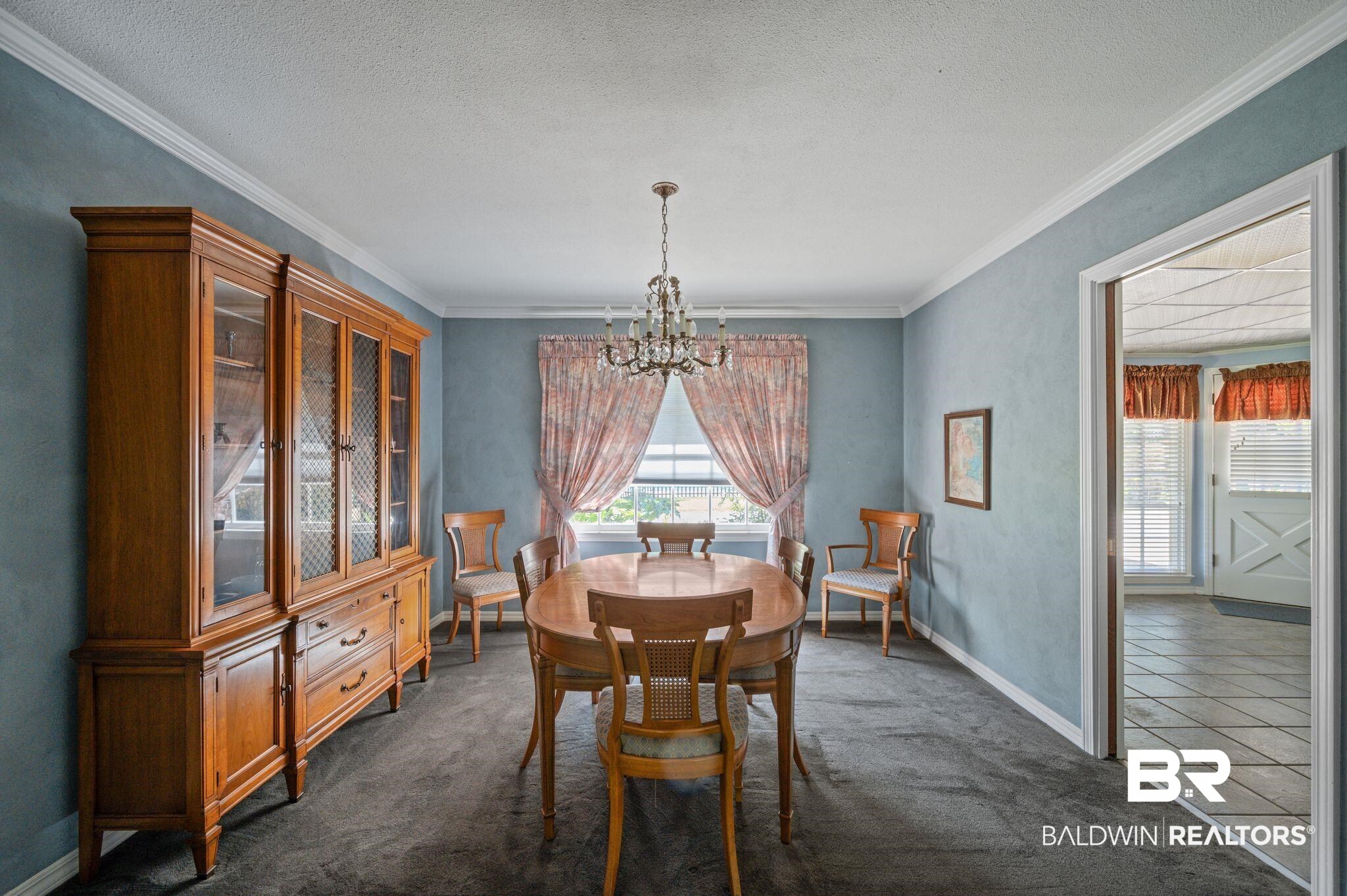 950 Walter Smith Road Mobile, AL 36695 - Photo 11 of 51 Dining area featuring a chandelier, crown molding, dark carpet, baseboards, and a textured ceiling