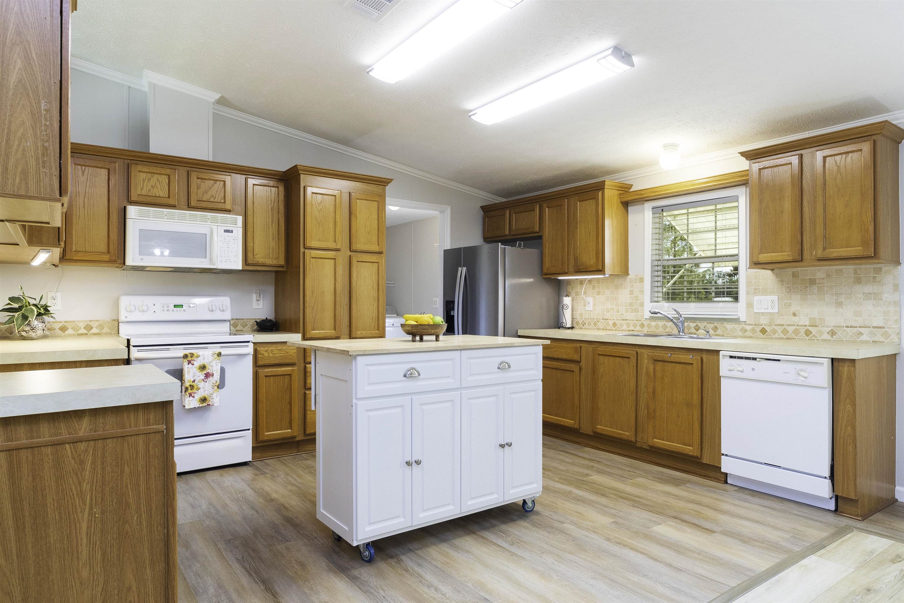 2232 Whippoorwill Drive St. Augustine, FL 32084 - Photo 9 of 51 a kitchen with a stove a sink wooden floor cabinets and a window
