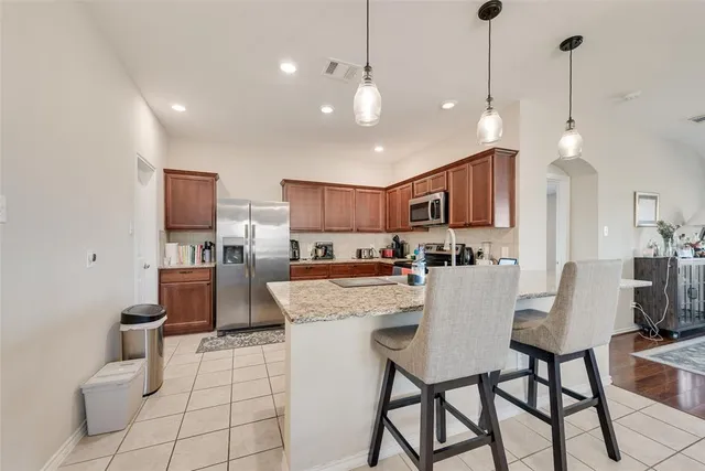 a view of kitchen with stainless steel appliances granite countertop a stove a sink dishwasher a dining table and chairs with wooden floor