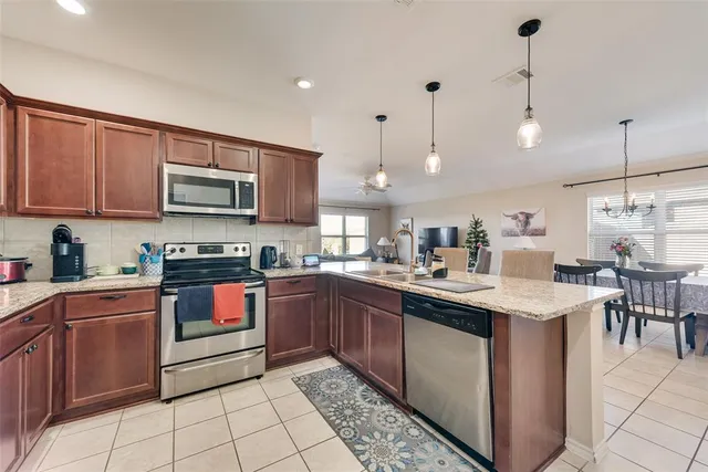 a kitchen with stainless steel appliances granite countertop a sink a stove top oven a counter space and cabinets