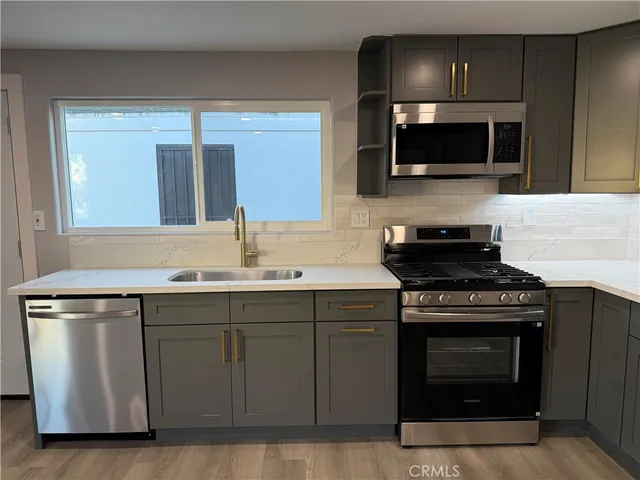 a kitchen with stainless steel appliances a stove a sink and a microwave