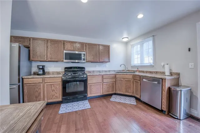 a kitchen with granite countertop wooden floors a stove and a microwave