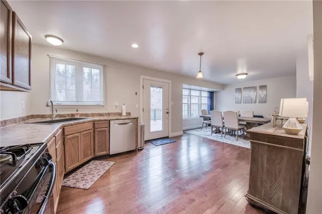 a living room with stainless steel appliances granite countertop furniture wooden floor and a window