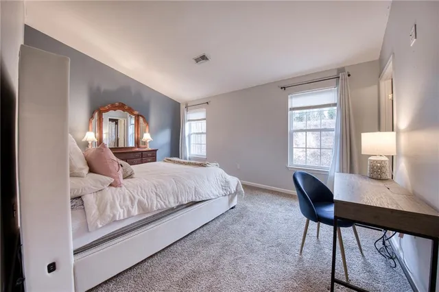 a bedroom with a bed a mirror on desk and a window