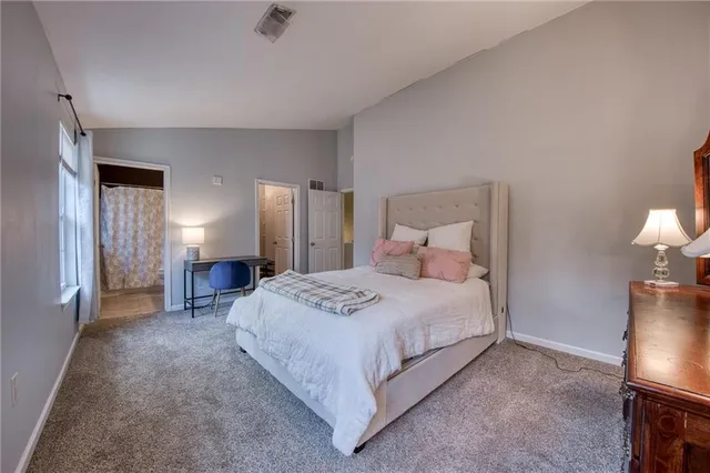 a spacious bedroom with a bed and a lamp on table