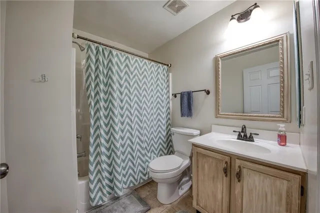 a bathroom with a sink a toilet a mirror and shower curtain