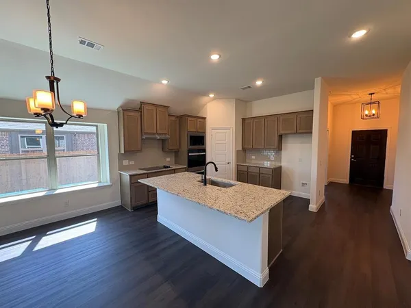 a large kitchen with kitchen island a large counter top space a sink stainless steel appliances and cabinets