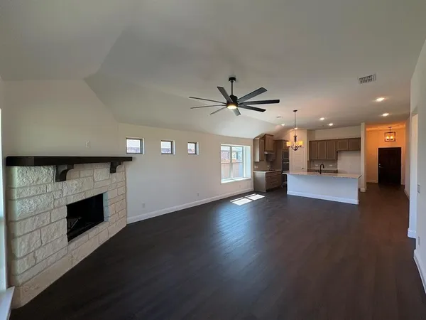 an empty room with wooden floor a fireplace and windows