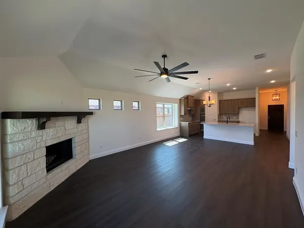 an empty room with wooden floor a fireplace and windows