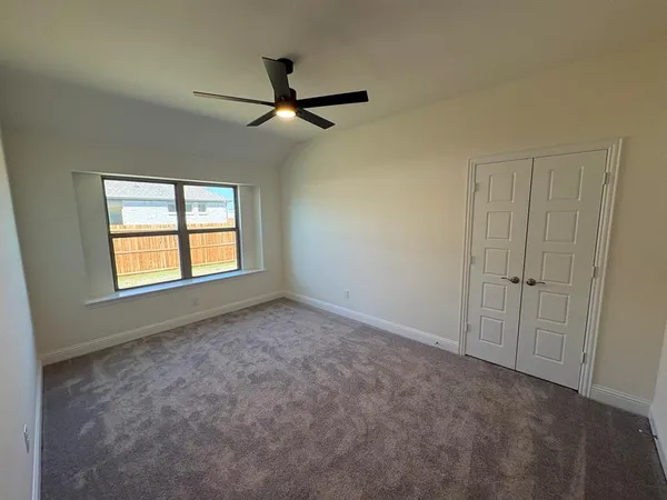 a view of empty room with window and ceiling fan