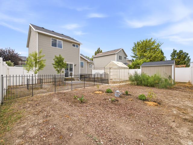 392 West Bricker Road Draper, UT 84020 - Photo 27 of 33 Spacious backyard featuring a storage shed, a greenhouse structure, and a perimeter of white privacy fencing