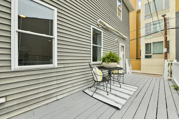 a patio with table and chairs and potted plants with wooden floor