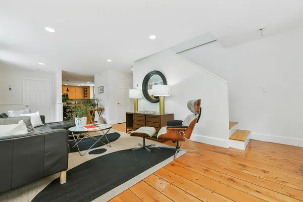 a living room with furniture a rug potted plant and a large window