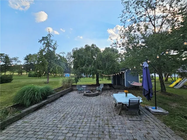a view of a wooden house with a big yard and large trees