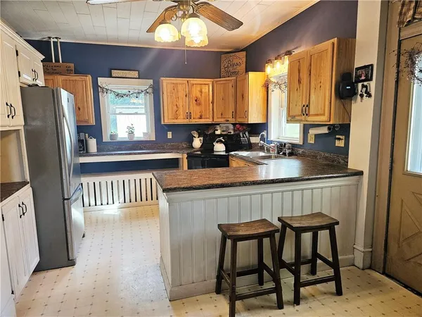 a kitchen with a refrigerator a sink dishwasher a dining table and chairs with wooden floor