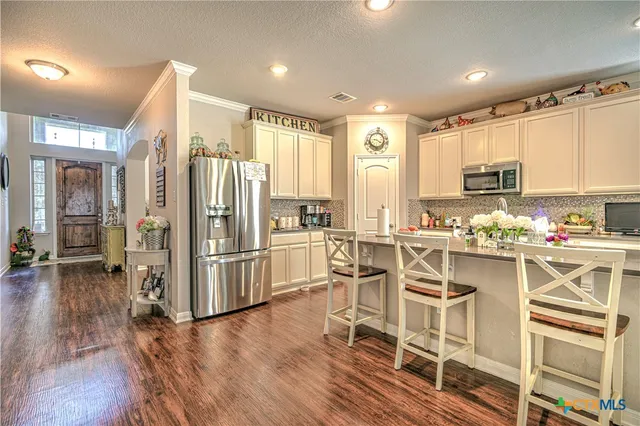 a kitchen with a refrigerator a stove a sink and white cabinets with wooden floor