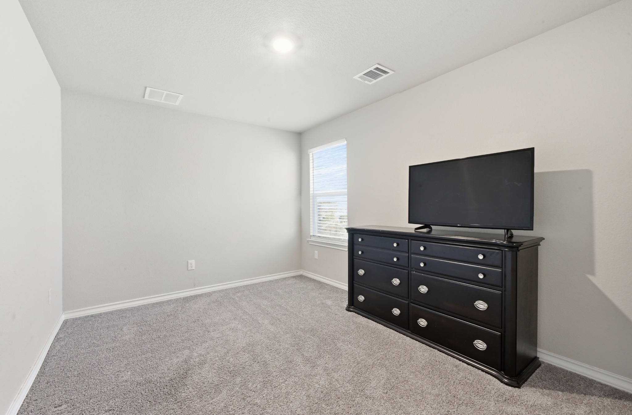 488 Pepperbark Loop Buda, TX 78610 - Photo 24 of 31 A well-lit bedroom features plush carpeting and a bright window.