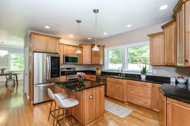 a kitchen with granite countertop a stove a sink a refrigerator and wooden cabinets
