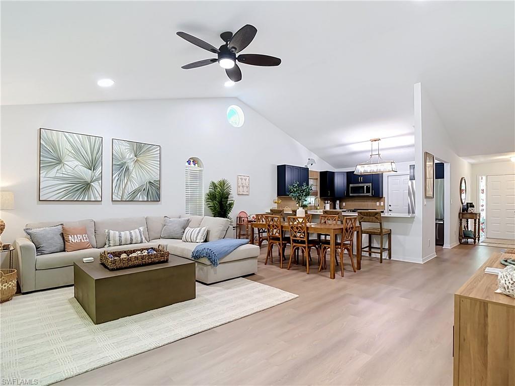 812 102nd Avenue North Naples, FL 34108 - Photo 5 of 33 Vaulted ceilings, recessed lighting, wood-finish flooring, dark blue cabinetry, and a kitchen island with a breakfast bar