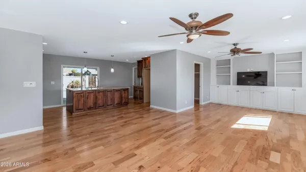 a view of an empty room with wooden floor and a ceiling fan