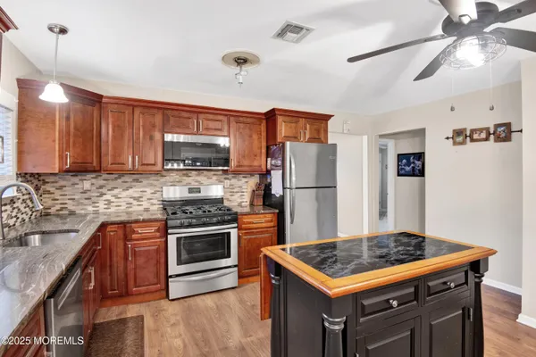 a kitchen with stainless steel appliances granite countertop a sink a stove a dining table and chairs