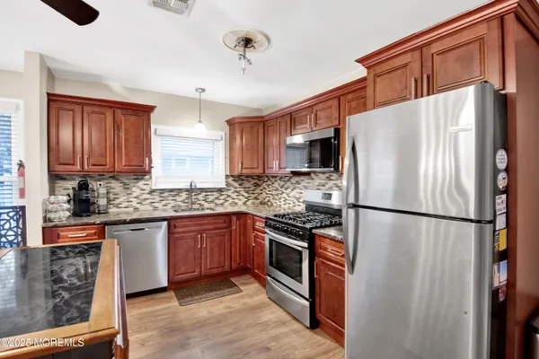 a kitchen with stainless steel appliances granite countertop a sink a stove a dining table and chairs with wooden floor