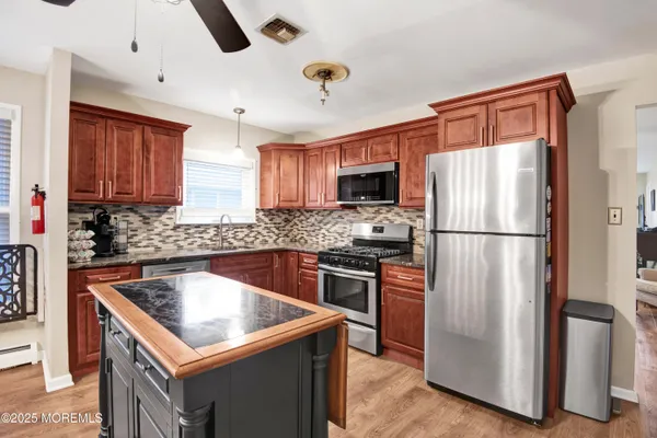 a kitchen with stainless steel appliances granite countertop a dining table chairs refrigerator and cabinets
