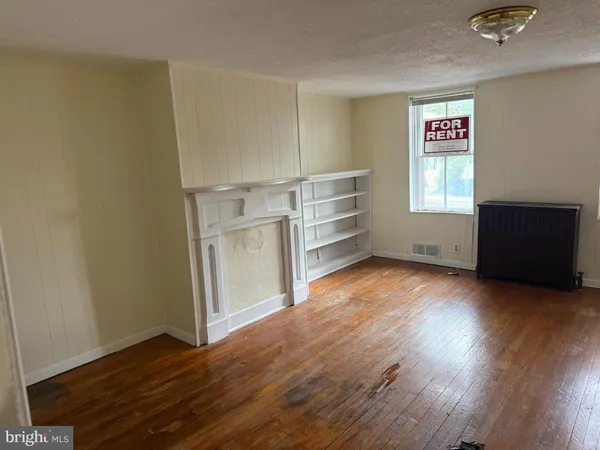 an empty room with wooden floor closet and windows