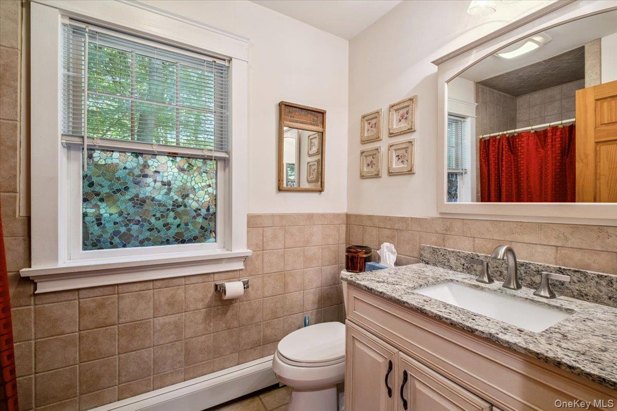 342 Lake Shore Road Putnam Valley, NY 10579 - Photo 18 of 46 Full bath featuring tile walls, vanity, a baseboard radiator, a wainscoted wall, and curtained shower