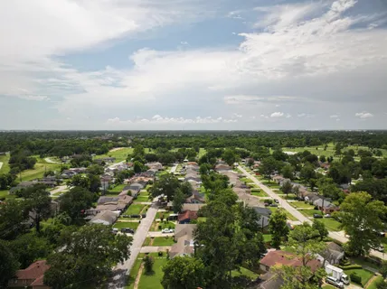 an aerial view of residential houses with outdoor space and trees