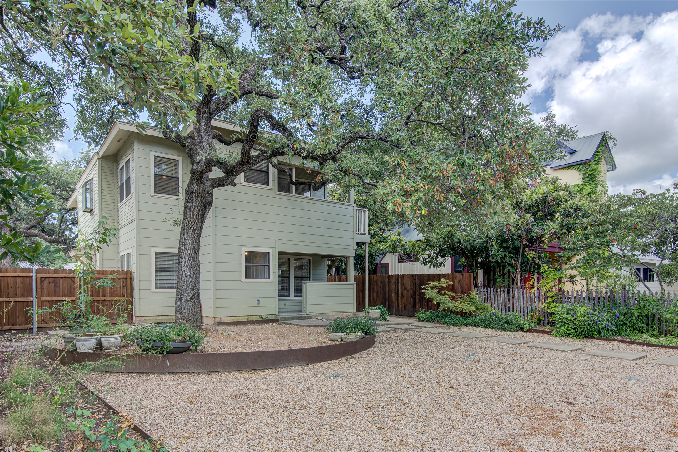 311 West Mary Street Austin, TX 78704 - Photo 3 of 35 A tranquil haven with a charming light green exterior, enveloped by mature, verdant trees.