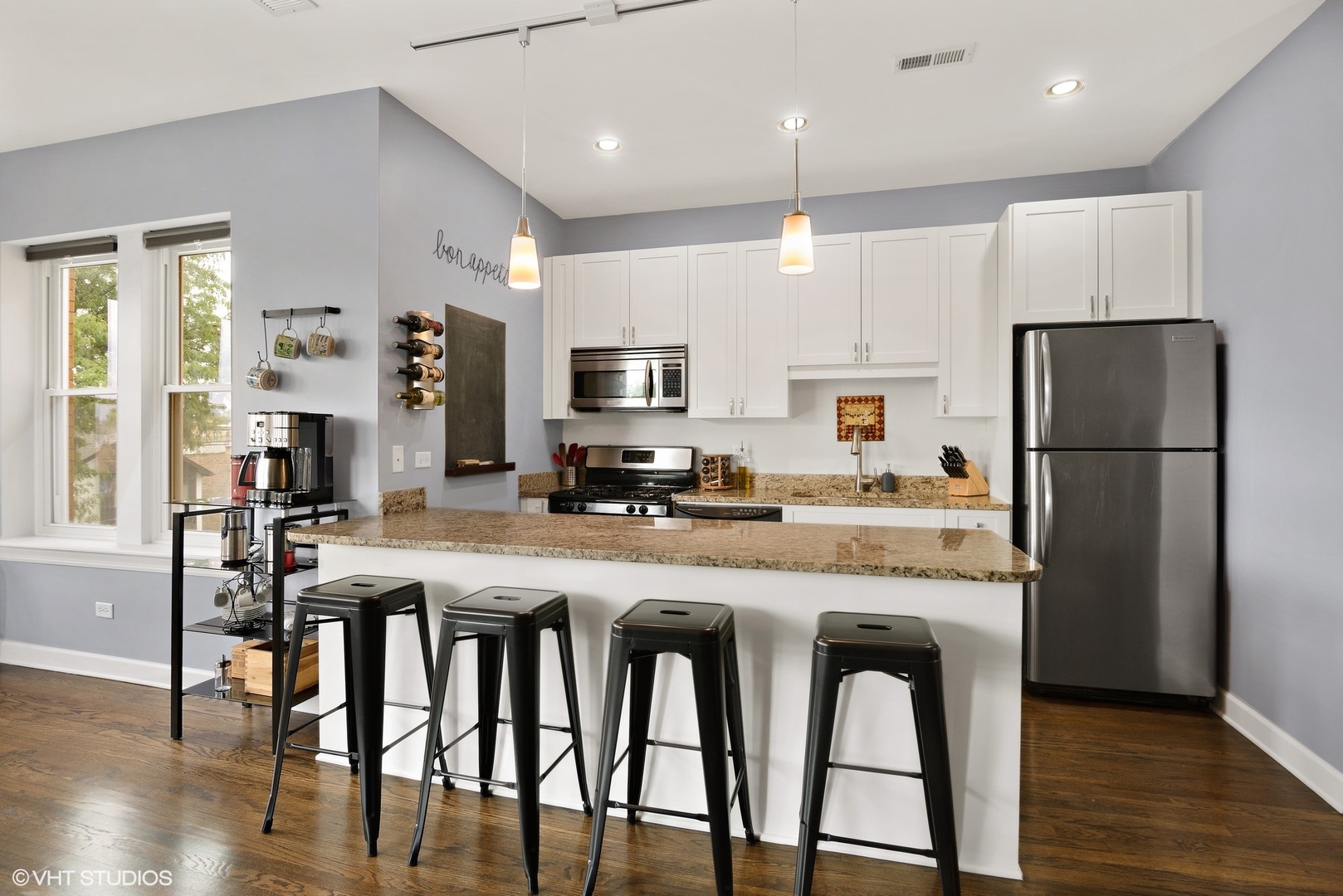 2116 North Spaulding Avenue, Unit 21163 Chicago, IL 60647 - Photo 5 of 18 a kitchen with stainless steel appliances granite countertop a dining table chairs refrigerator and microwave