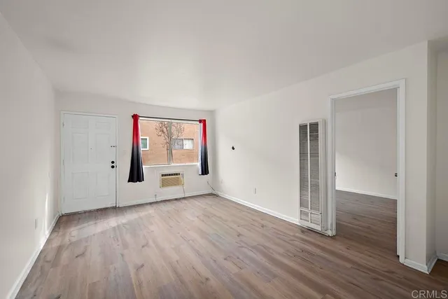 an empty room with wooden floor and window