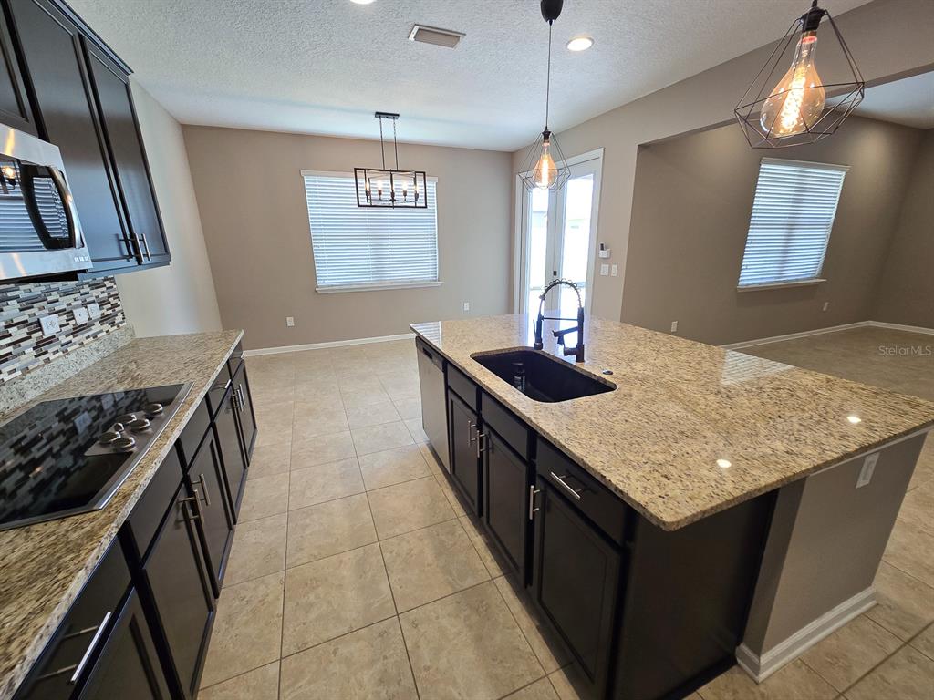 3543 Meadow Breeze Loop Ocoee, FL 34761 - Photo 12 of 38 a kitchen with stainless steel appliances granite countertop a sink a stove and a wooden cabinets