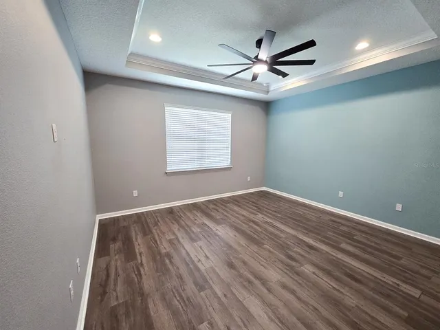 an empty room with wooden floor ceiling fan and windows